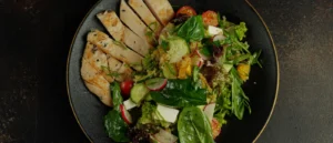 Ensalada con pollo y verduras frescas presentada en un plato oscuro